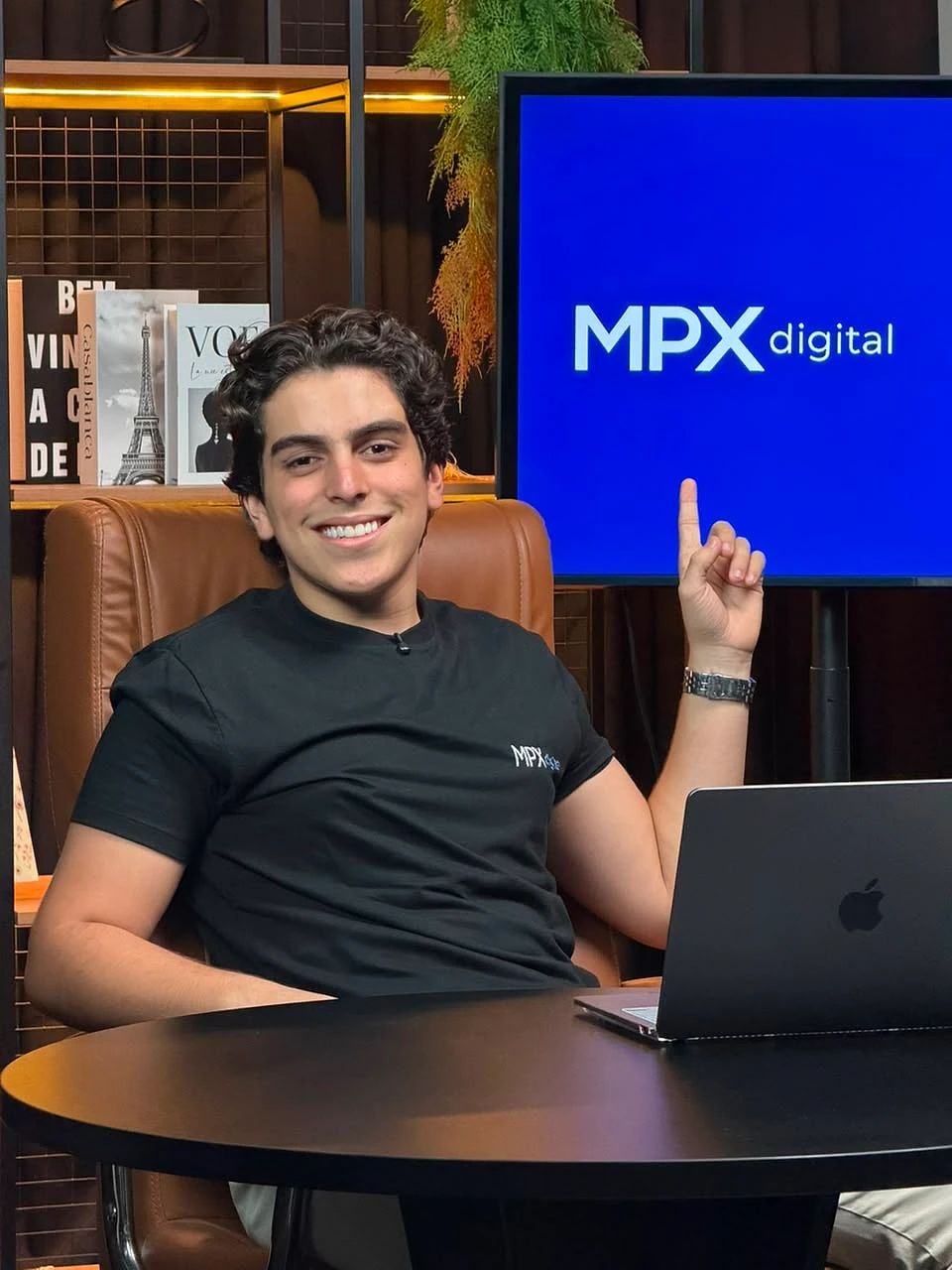 Mateus Paculdino, da MPX Digital, no estúdio da empresa, com a marca MPX Digital exibida no telão ao fundo